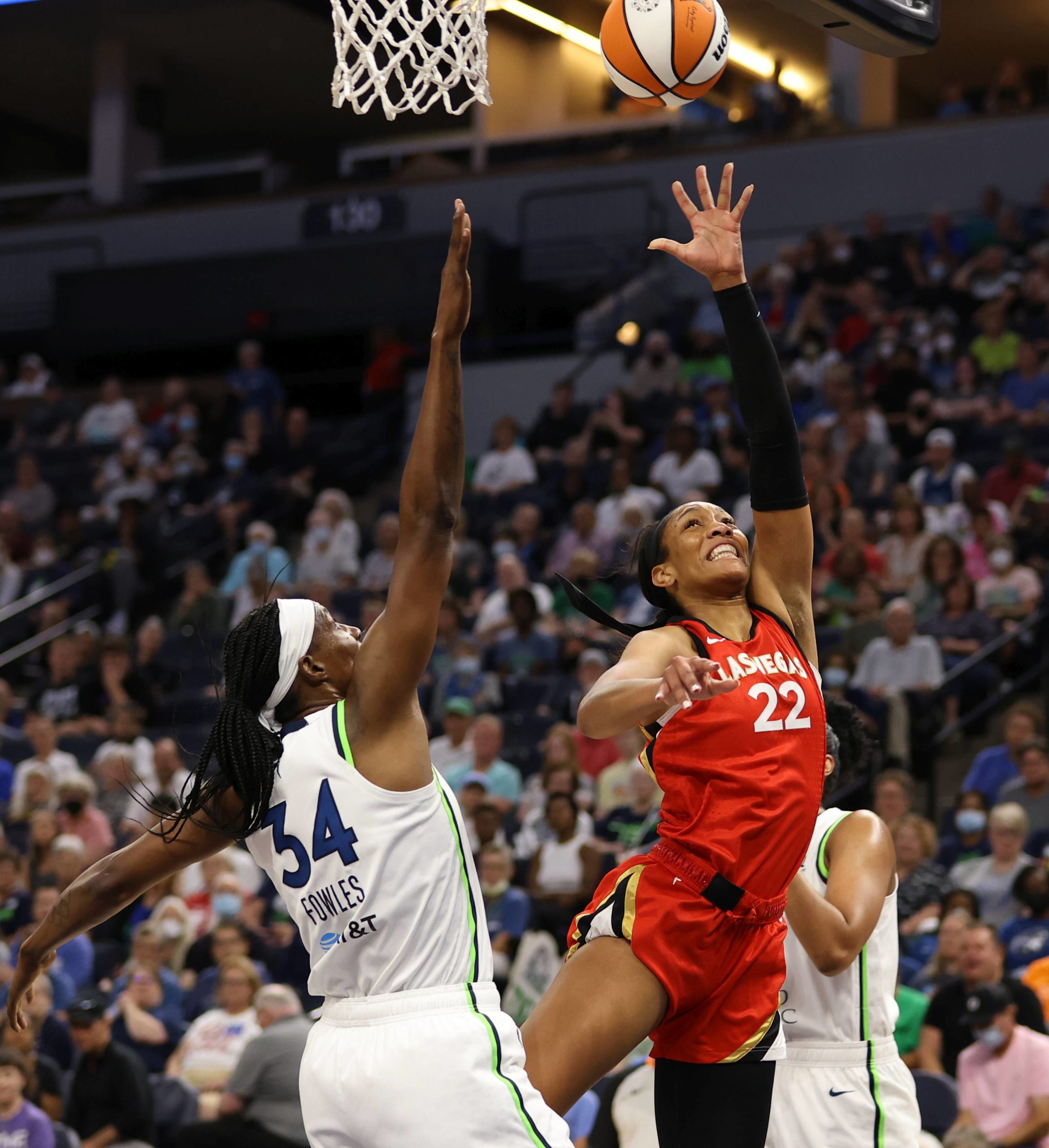 Aces center A'ja Wilson (22) goes for a layup, her right hand outstretched. Lynx center Sylvia Fowles (34) contests the shot with her right hand.