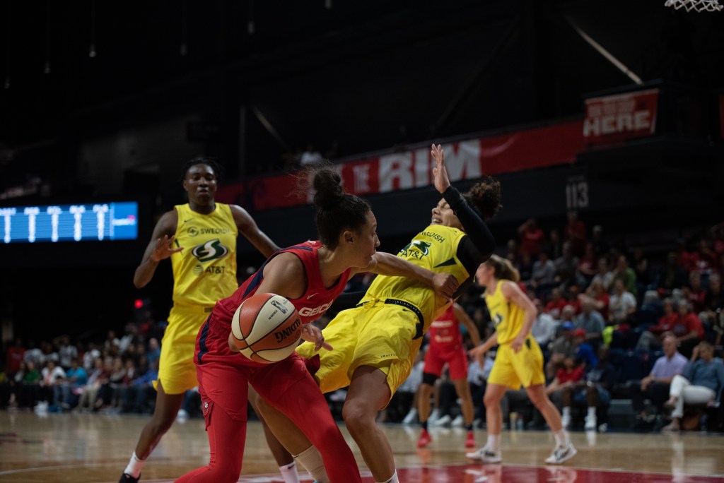 Seattle Storm wing Alysha Clark (right) absorbs contact from Washington Mystics wing Aerial Powers during a game at the Entertainment and Sports Arena in Washington, D.C., on June 14, 2019. (Photo credit: Domenic Allegra)