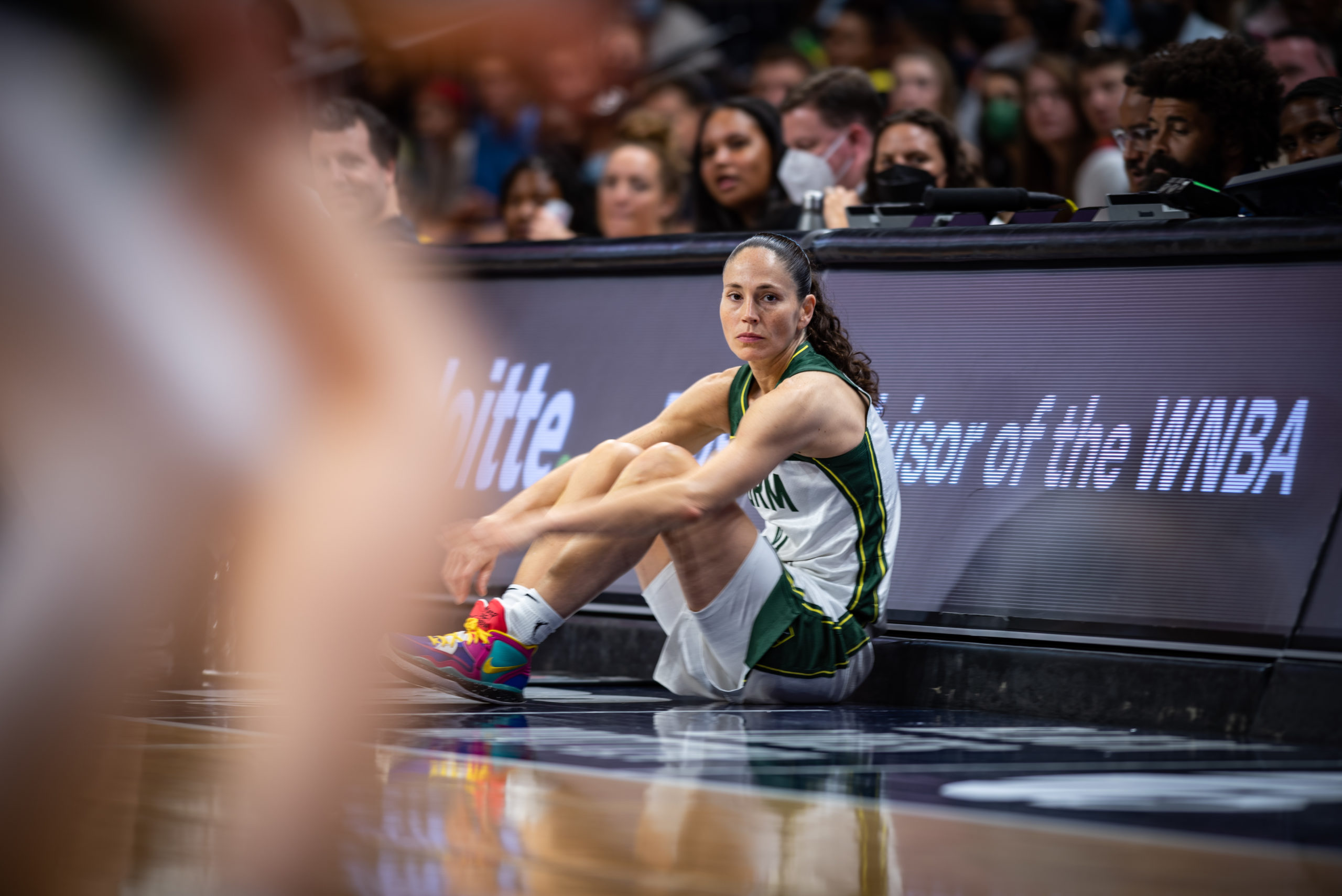 Seattle Storm point guard Sue Bird (10) sits pensively by the scorers table with her arms around her knees.