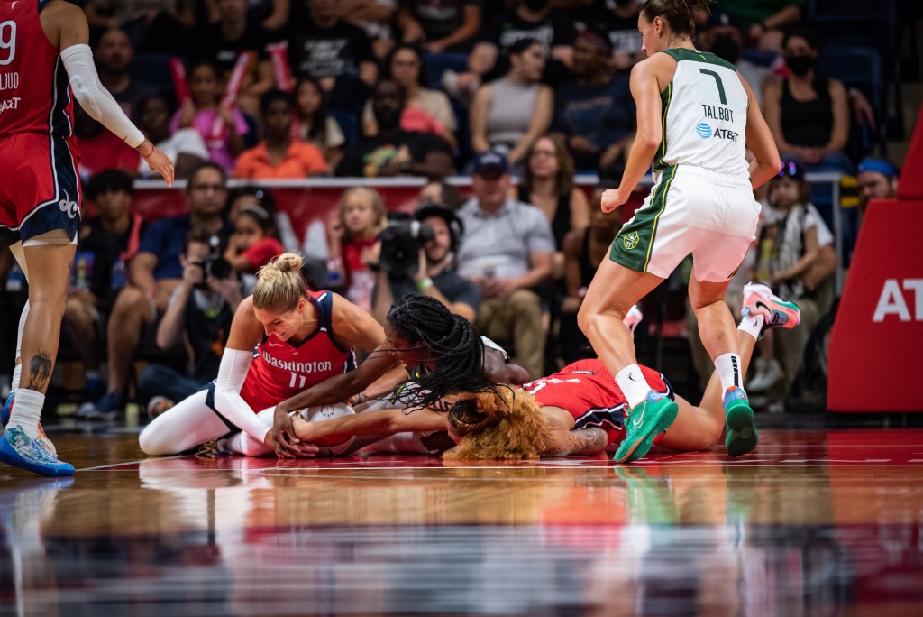 Mystics big Elena Delle Donne (11), center Shakira Austin (0), and Storm center Ezi Magbegor (13) dive for a rebound. Storm forward Stephanie Talbot (7) stands nearby.