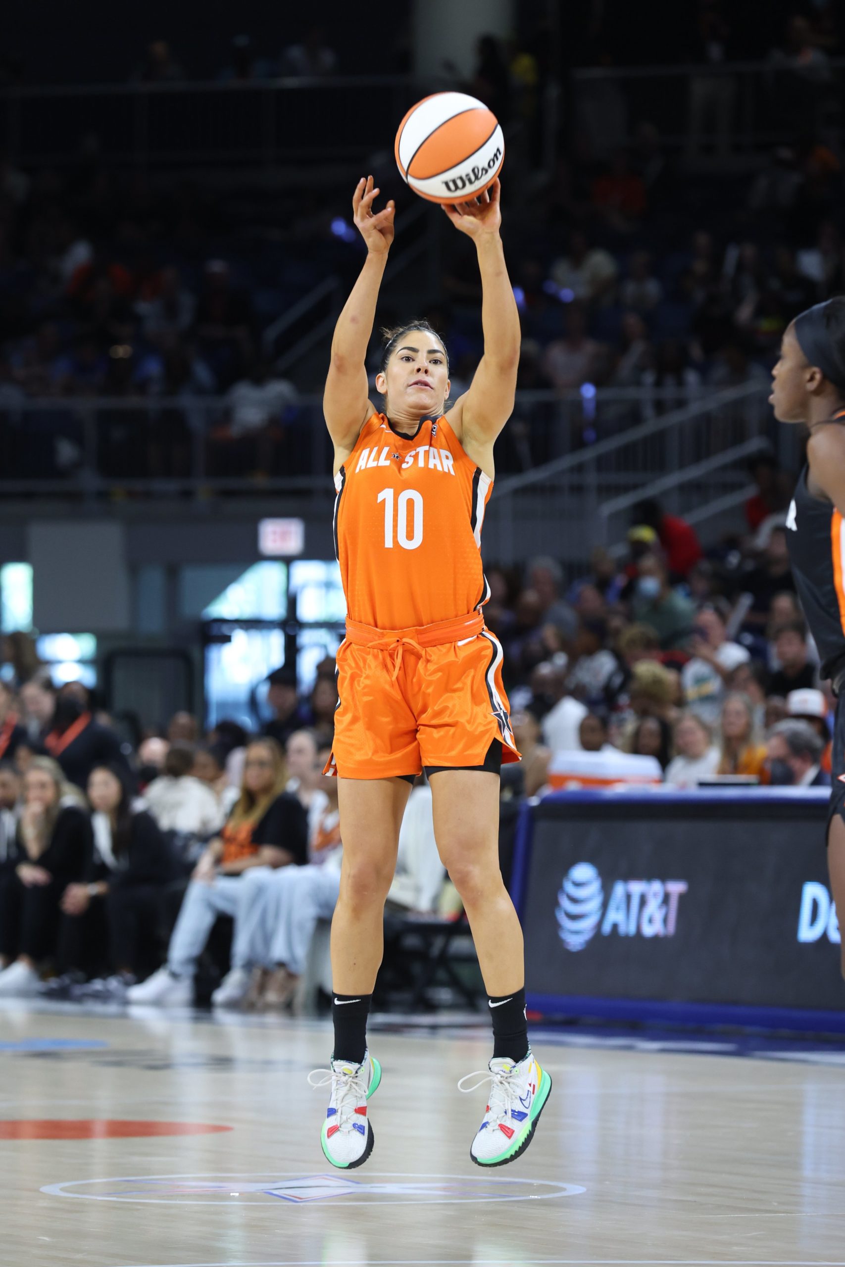 Team Wilson point guard Kelsey Plum, mid-air, releases a three off her fingertips in the All-Star game