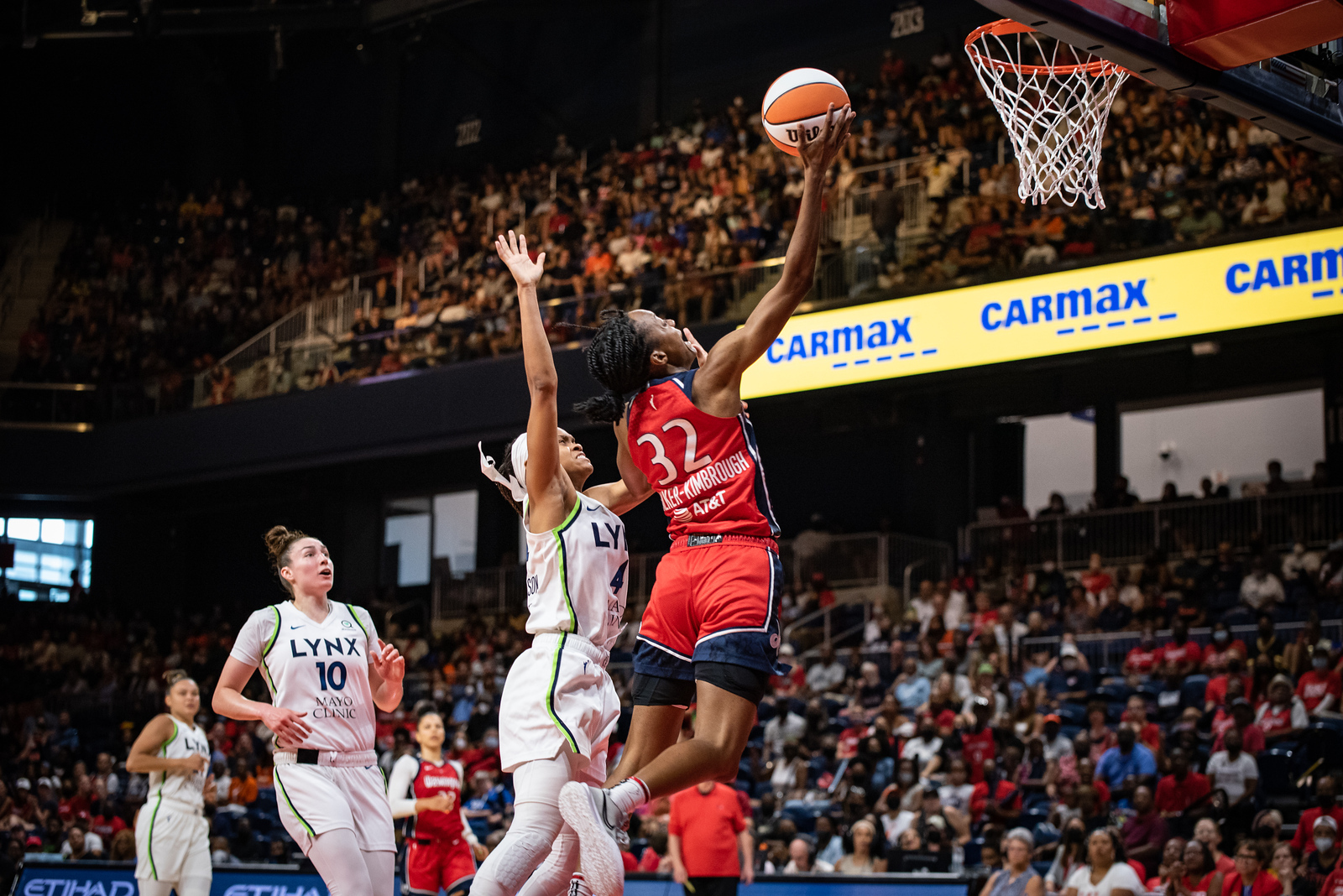 Washington Mystics guard Shatori Walker-Kimbrough shoots a right-handed layup. Minnesota Lynx point guard Moriah Jefferson contests the shot, and Lynx combo forward Jessica Shepard looks on from behind.