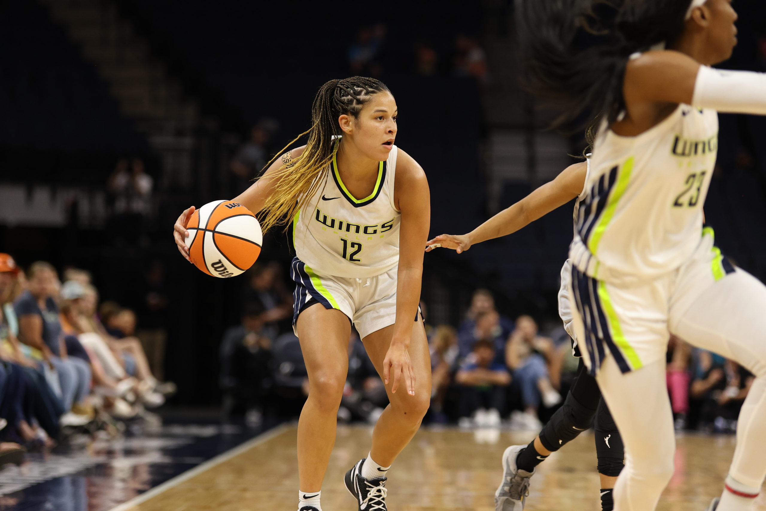 Dallas point guard Veronica Burton has the ball at the top of her dribble, crouched over and looking across the court from near the high corner of halfcourt, while Wings off-ball guard Jasmine Dickey sprints down the sideline in front of her