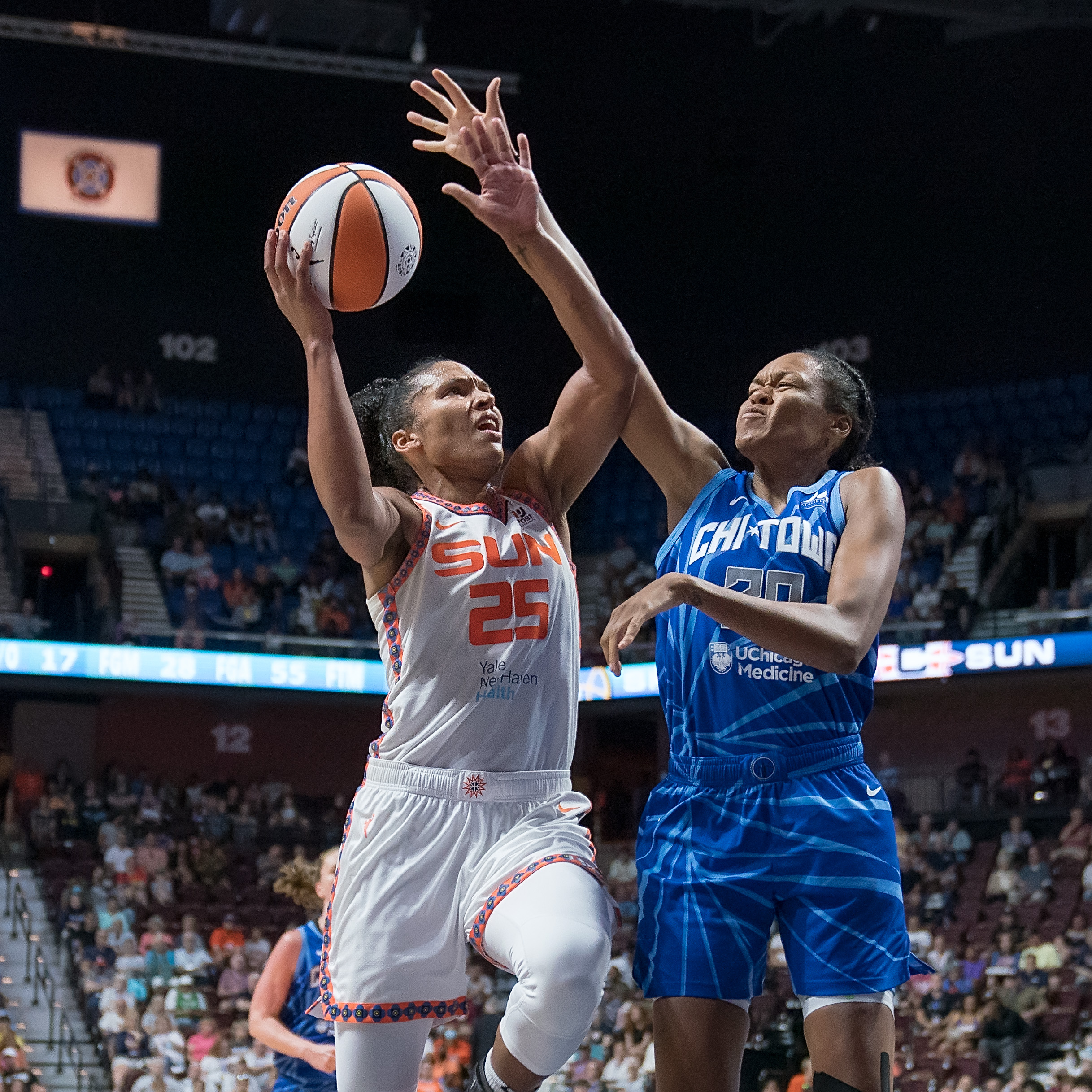 Sun forward Alyssa Thomas (25) goes for a layup over Sky big Azura Stevens. Stevens attempts to block the shot with her right hand.