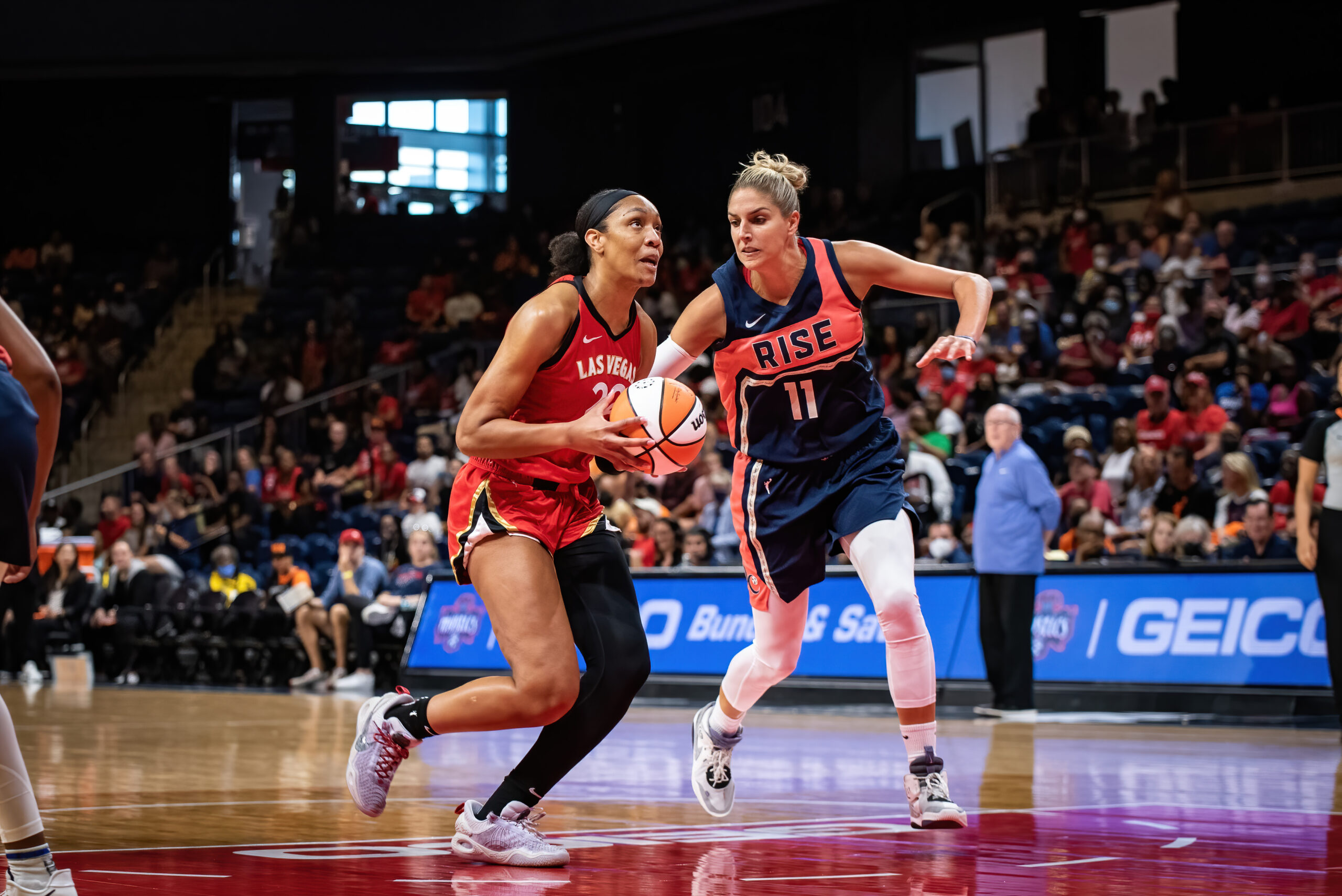 Las Vegas center A'ja Wilson holds the ball in front of her midsection and looks up towards the rim as she runs down from the free-throw line, as Washington Mystics big Elena Delle Donne tries to catch up from behind