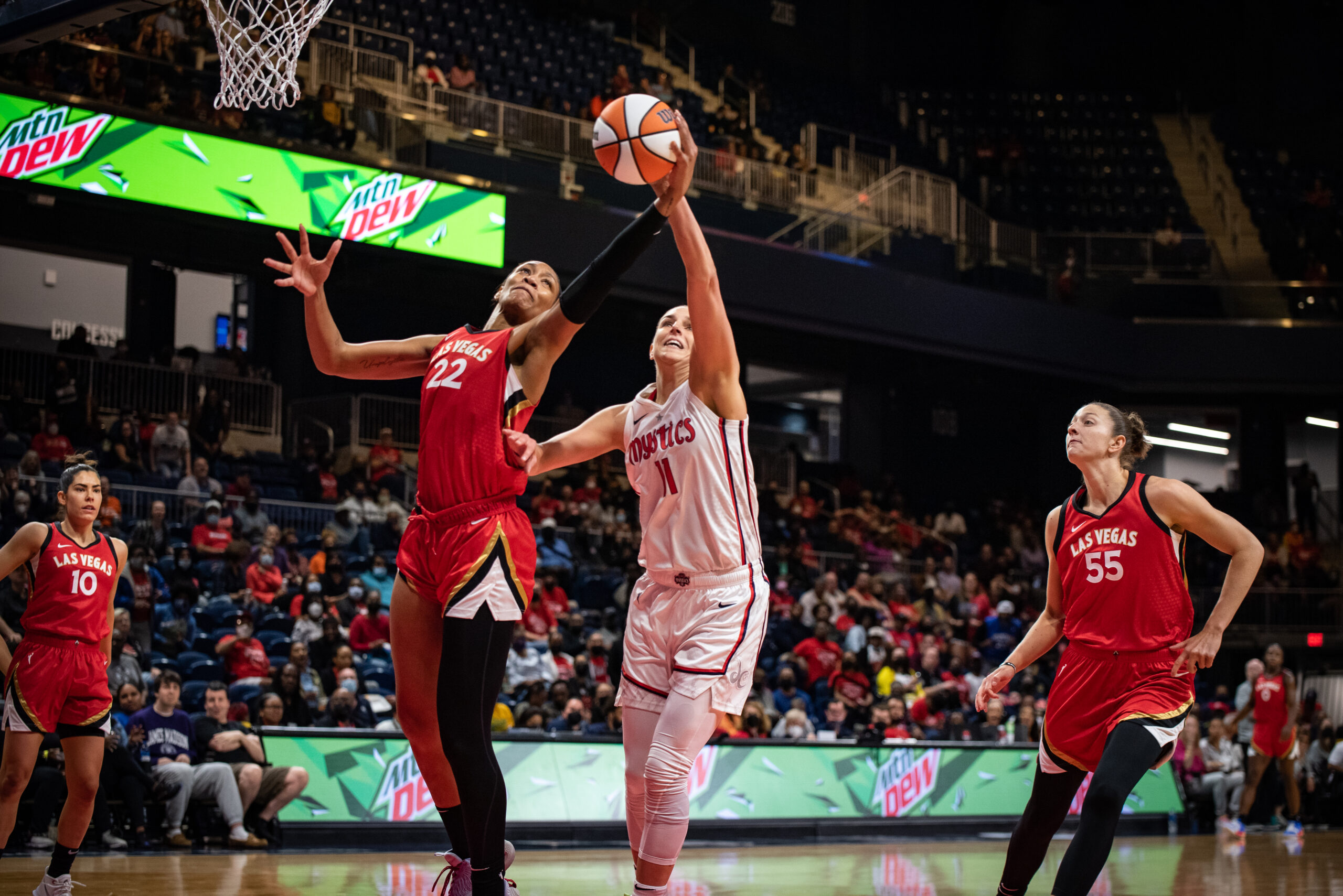 Aces center A'ja Wilson (22) and Mystics big Elena Delle Donne reach for an offensive rebound. Aces forward Theresa Plaisance (55) and point guard Kelsey Plum (10) stand behind them.
