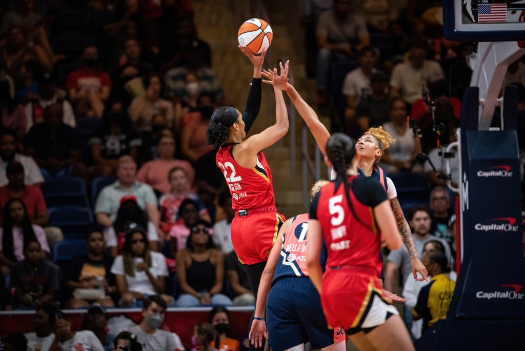 Las Vegas Aces center A'ja Wilson shoots a fadeaway jumper off her fingertips, as Washington Mystics center Shakira Austin reaches out towards her with an outstretched arm in an attempt to contest the shot.