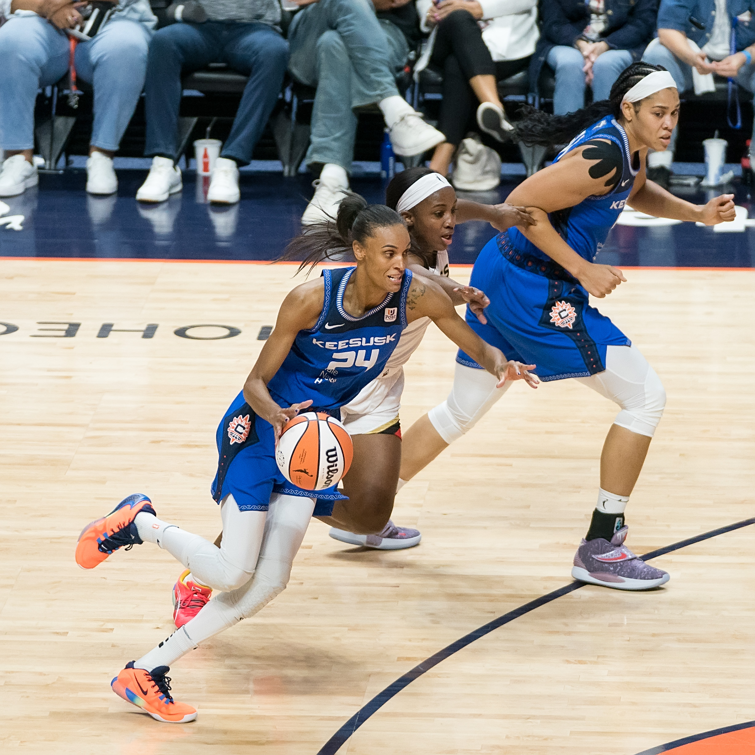 Sun forward DeWanna Bonner (24) drives to the basket as Aces wing Jackie Young (0) defends. Sun center Brionna Jones (42) runs toward the basket on the opposite side of Young from Bonner.