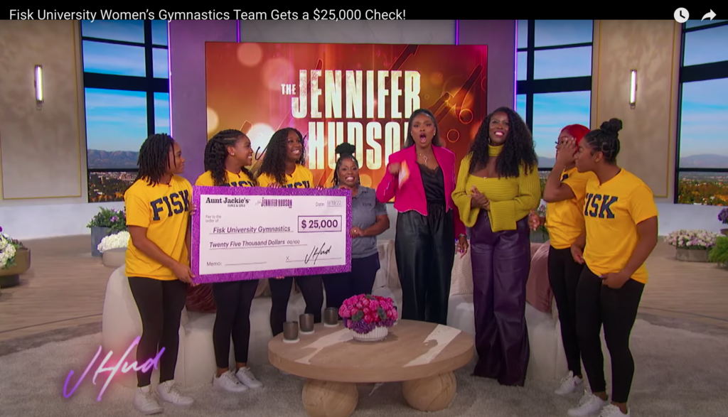 Members of the Fisk Gymdogs and their head coach Corrine Tarver Wright (center, in gray) accepting a $25,000 check from Aunt Jackie's CMO Kendria Strong (third from right) on The Jennifer Hudson Show. 