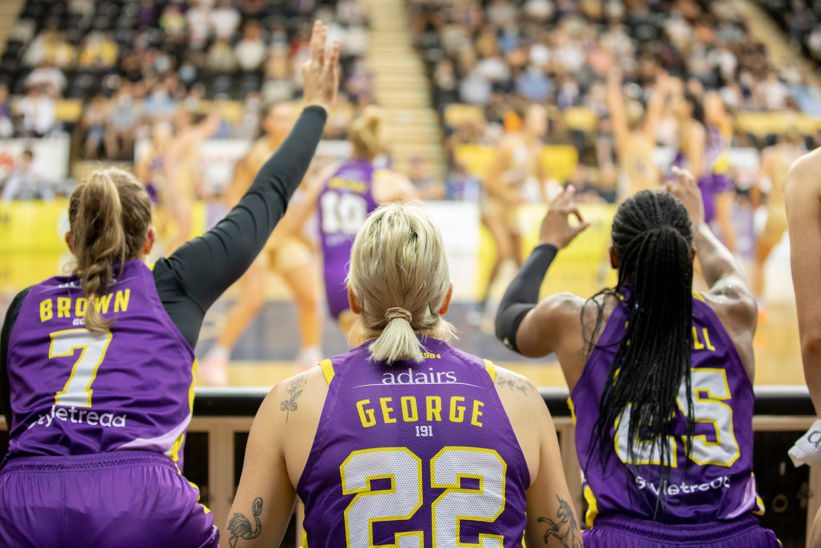 Lou Brown (7), Cayla George (22) and Tiffany Mitchell (25) of the Melbourne Boomers cheer on their teammates from the sidelines.