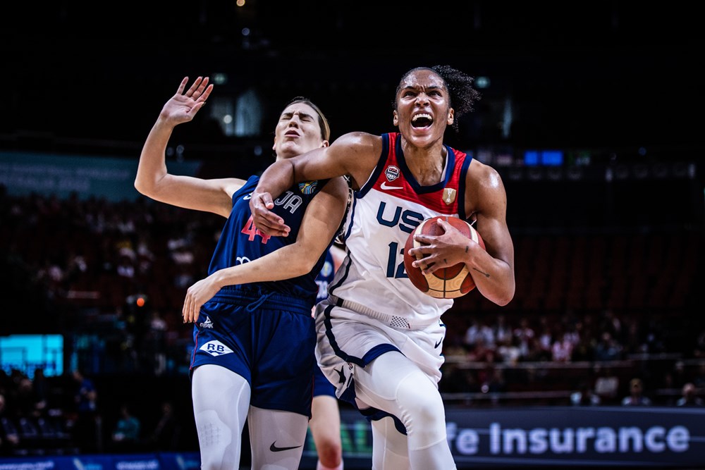 USA's Alyssa Thomas holds the ball in her left hand and holds off a defender with her right arm.