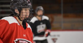 Saint Lawrence University players prep for their home opener in red and white uniforms.