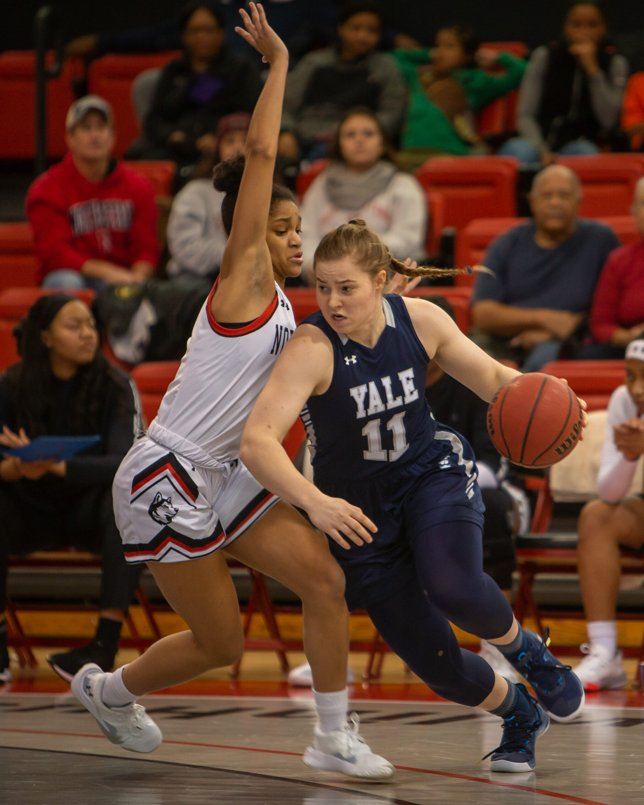 Yale guard Klara Astrom dribbles the ball in her left hand and drives past a Northeastern defender who is trying to stay vertical.