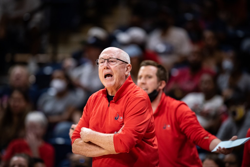 Then-Washington Mystics head coach Mike Thibault yells from the sideline with his arms crossed. Then-associate head coach Eric Thibault is behind him with his arms outstretched.