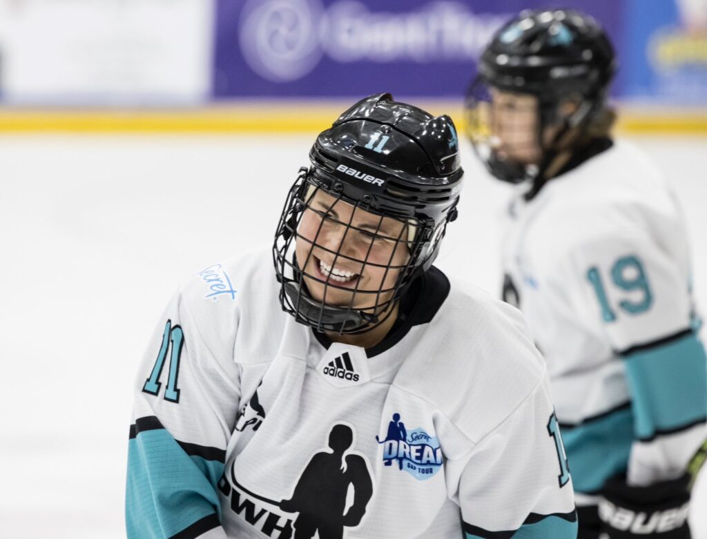 Hockey player Abby Roque is smiling in her jersey while skating on the ice during a recent PWHPA game.