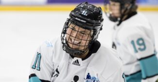 Hockey player Abby Roque is smiling in her jersey while skating on the ice during a recent PWHPA game.