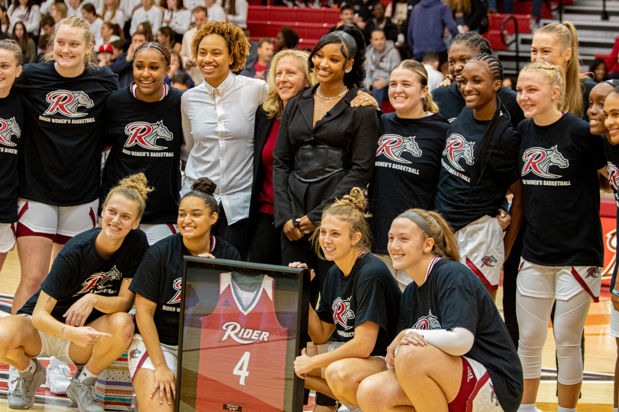 Stella Johnson (center) poses for a group photo with the current Rider women's basketball team.