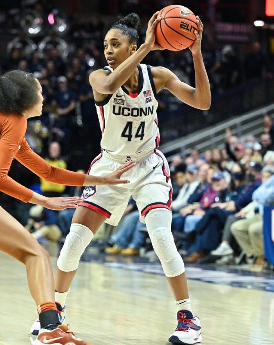 UConn junior establishes position on the court by swinging her arms up with the ball in hand. Griffin wears number 44 and is in a UConn red, white and blue uniform.