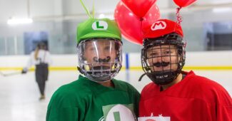 Two Buffalo Beauts players dressed up as Luigi and Mario, complete with hats, balloons and fake mustaches