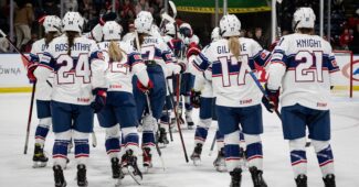 Members of the USA Hockey team gather on the ice in red, white and blue uniforms after a Rivalry Series victory.