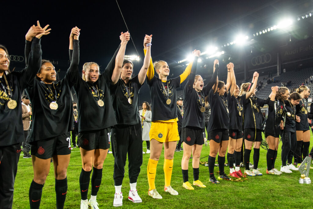Portland Thorns players hold hands and celebrate winning the 2022 NWSL Championship. (Photo Credit / Domenic Allegra)