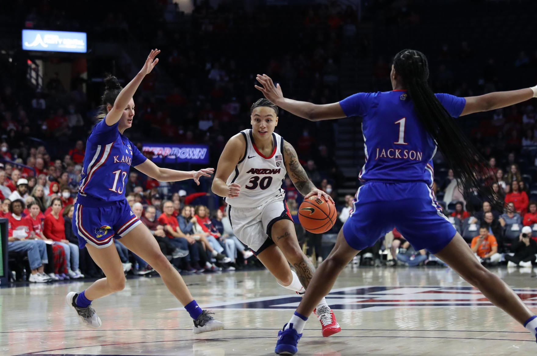 Fifth year transfer Jade Loville drives to the basket during Arizona's 77-50 loss to Kansas. She is wearing traditional red, white and blue home Arizona uniform colors.