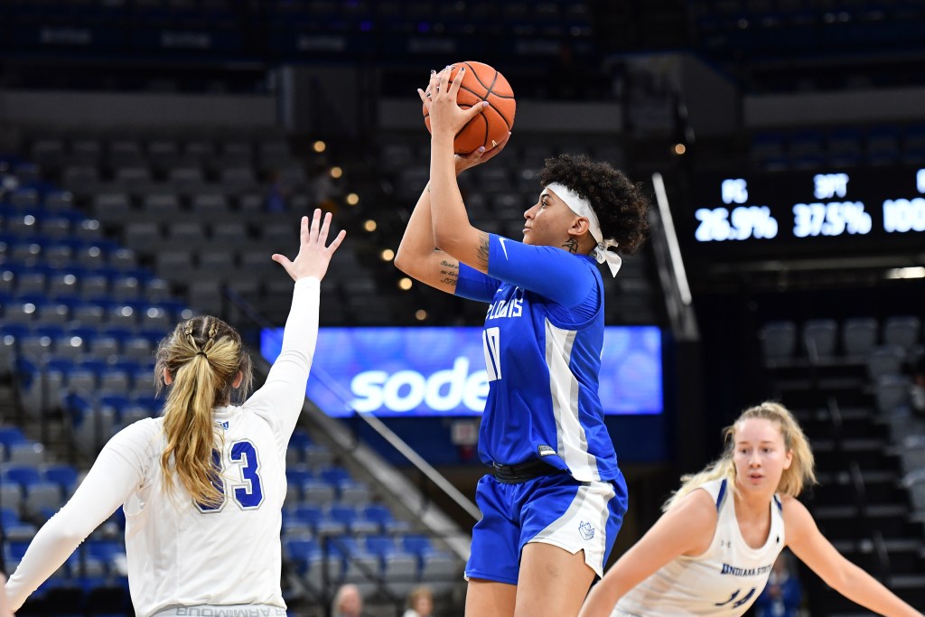 Kyla McMakin (blue uniform) puts up a shot over the raised hand of a defender