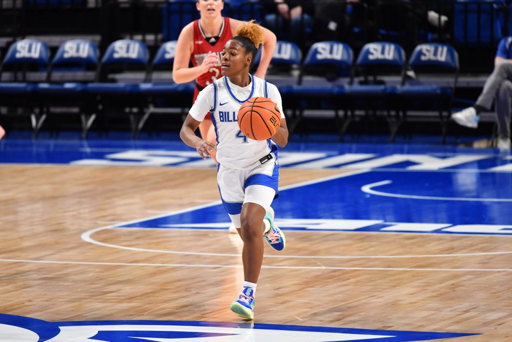 Kennedy Calhoun (white jersey with blue details) brings the ball up the court against South Dakota