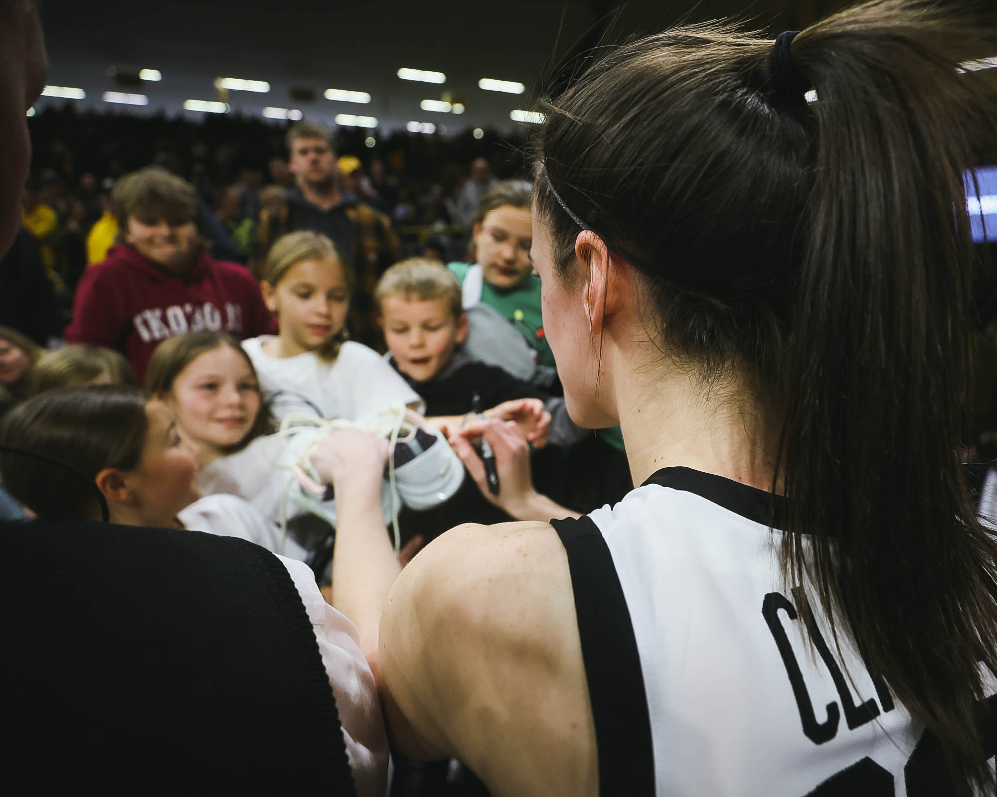 Caitlin Clark hands autographed shoes to a young fan
