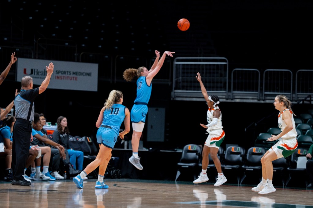 Columbia forward Hannah Pratt shoots an open 3-pointer as a Miami player arrives to contest. The official has one hand raised to signal a 3-point attempt.