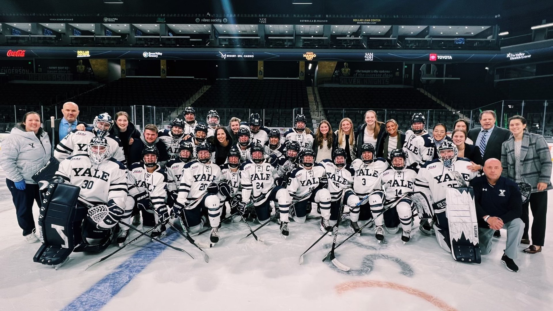 Yale women's hockey team poses on ice in Yale Blue and White jerseys.