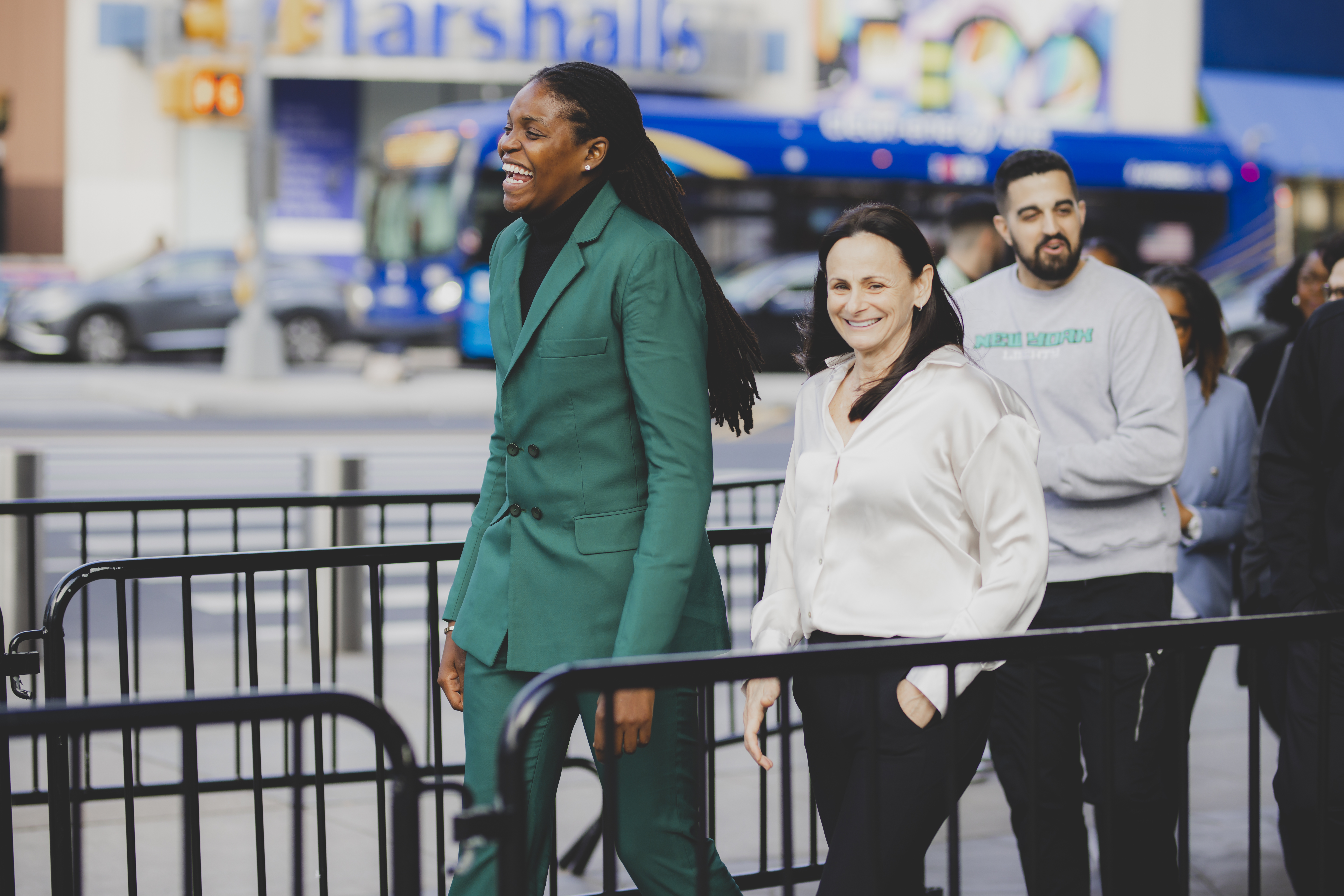 Jonquel Jones, wearing a teal green suit and a black turtleneck, walks up the street.
