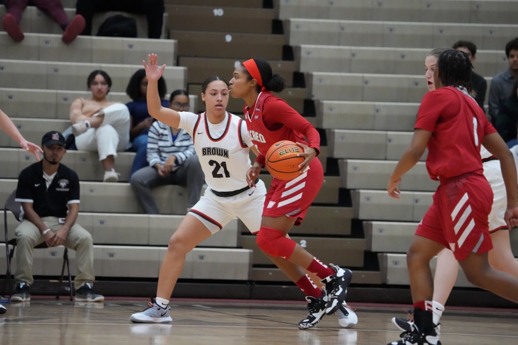 Brown guard Grace Arnolie moves laterally to defend a Sacred Heart player dribbling the ball.