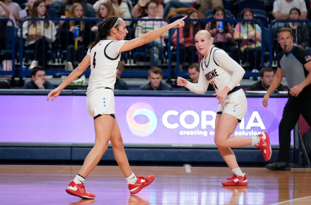 Megan McConnell (brunette) points down the court while teammate Tess Myers (blonde) runs down the court.