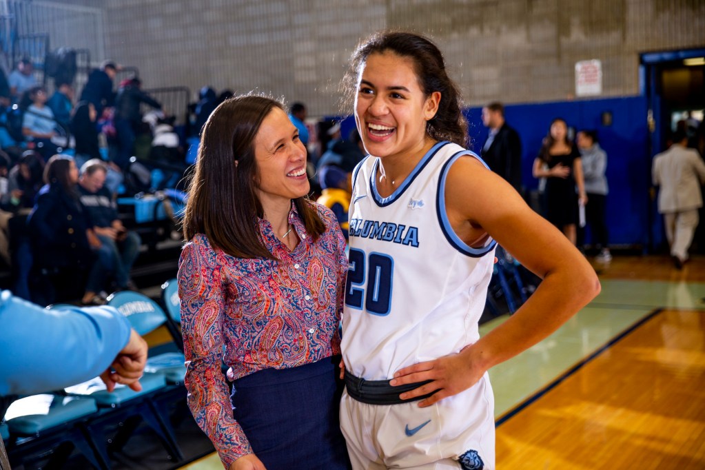 Megan Griffith and Sienna Durr stand next to each other and smile postgame, and Griffith looks up at Durr.