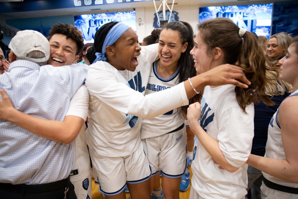 Lilian Kennedy, Sienna Durr and Mikayla Markham embrace as a crowd gathers on the court to celebrate a Columbia win.