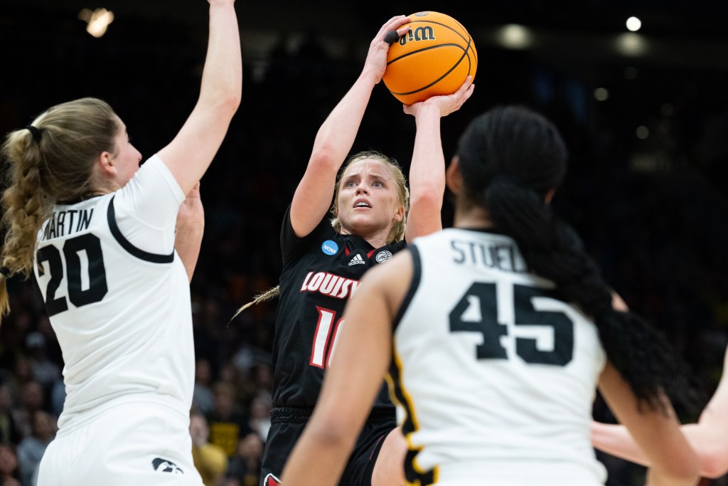 Hailey Van Lith takes a jump shot in the background with two Iowa defenders in the foreground.