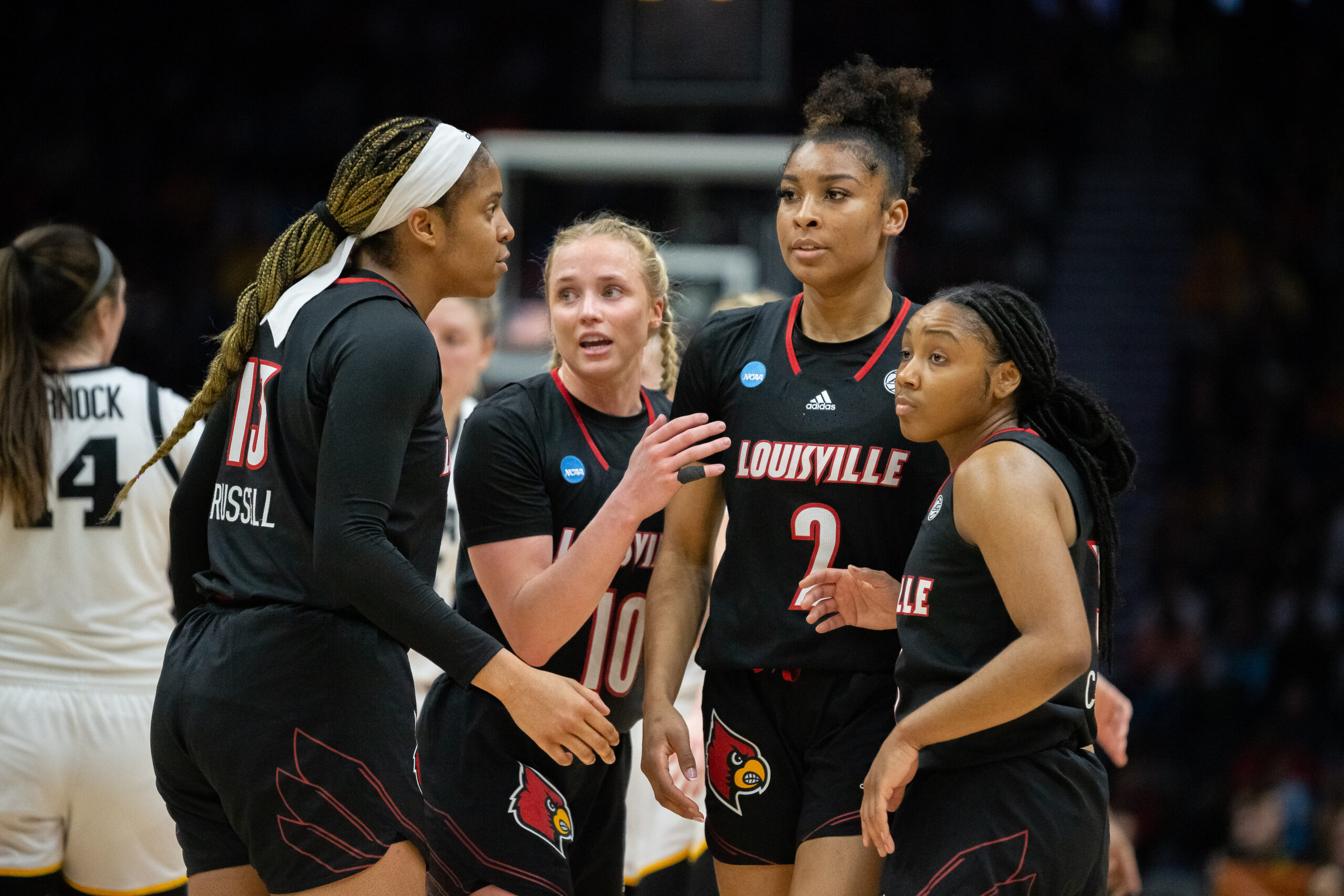 Merissah Russell, Hailey Van Lith, Nyla Harris, and Chrislyn Carr huddle up on the court.