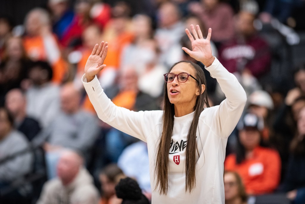 Harvard head coach Carrie Moore holds her hands up, giving instructions to her team.
