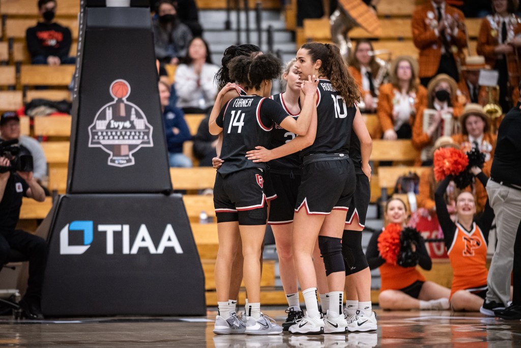 Five Harvard players huddle on the court.