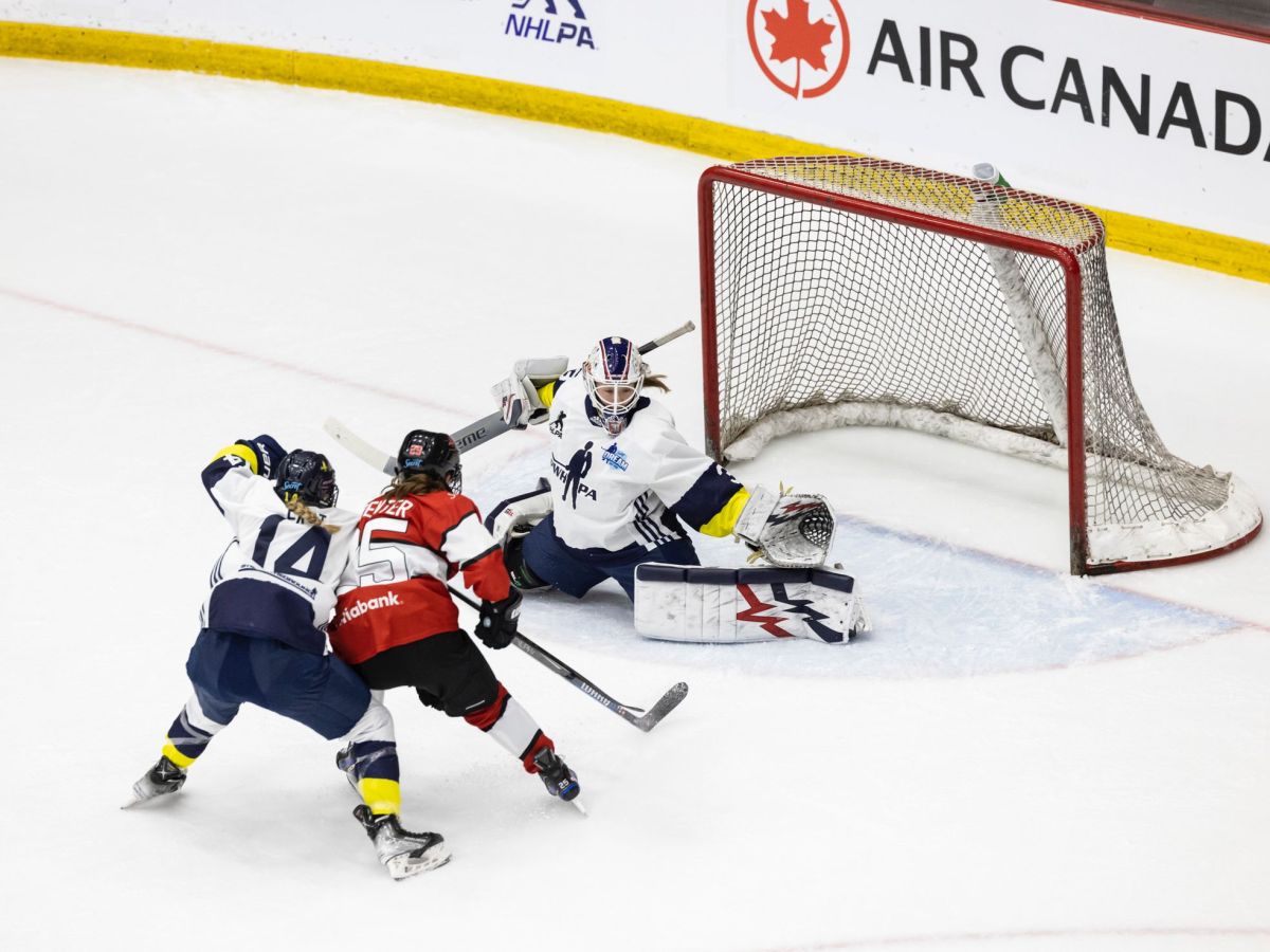A Scotiabank and Adidas player battle in front of Adidas goaltender Aerin Frankel who is stretched out infront of her net.