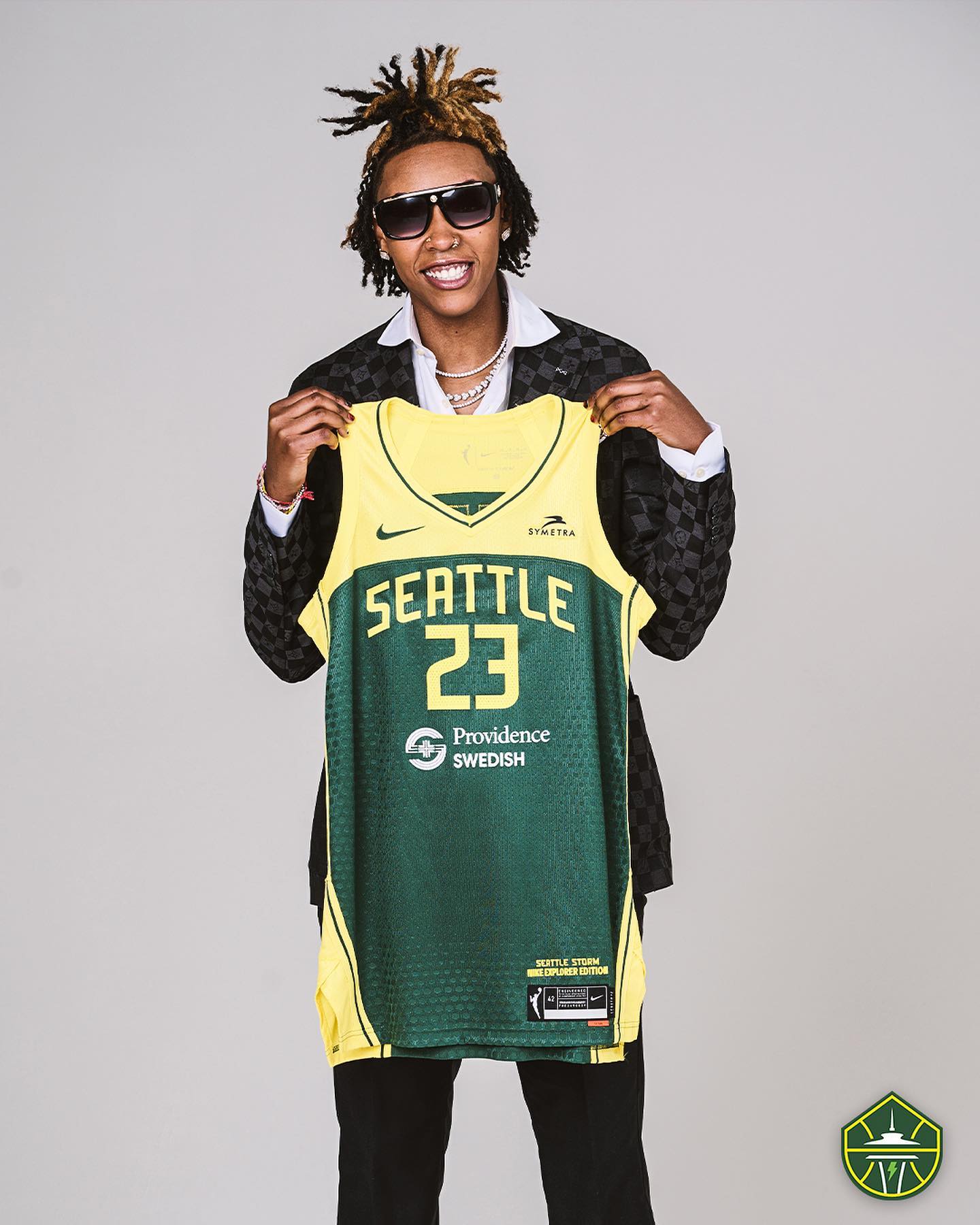 Seattle Storm draft pick Jordan Horston holds up a green and yellow No. 23 Storm jersey.
