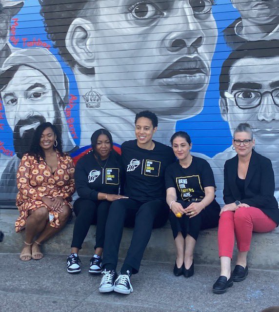 Brittney Griner poses alongside friends and families in front of a new mural outside of Phoenix's Footprint center. The mural features a Griner and the likeness of other U.S. citizens wrongfully detained abroad.