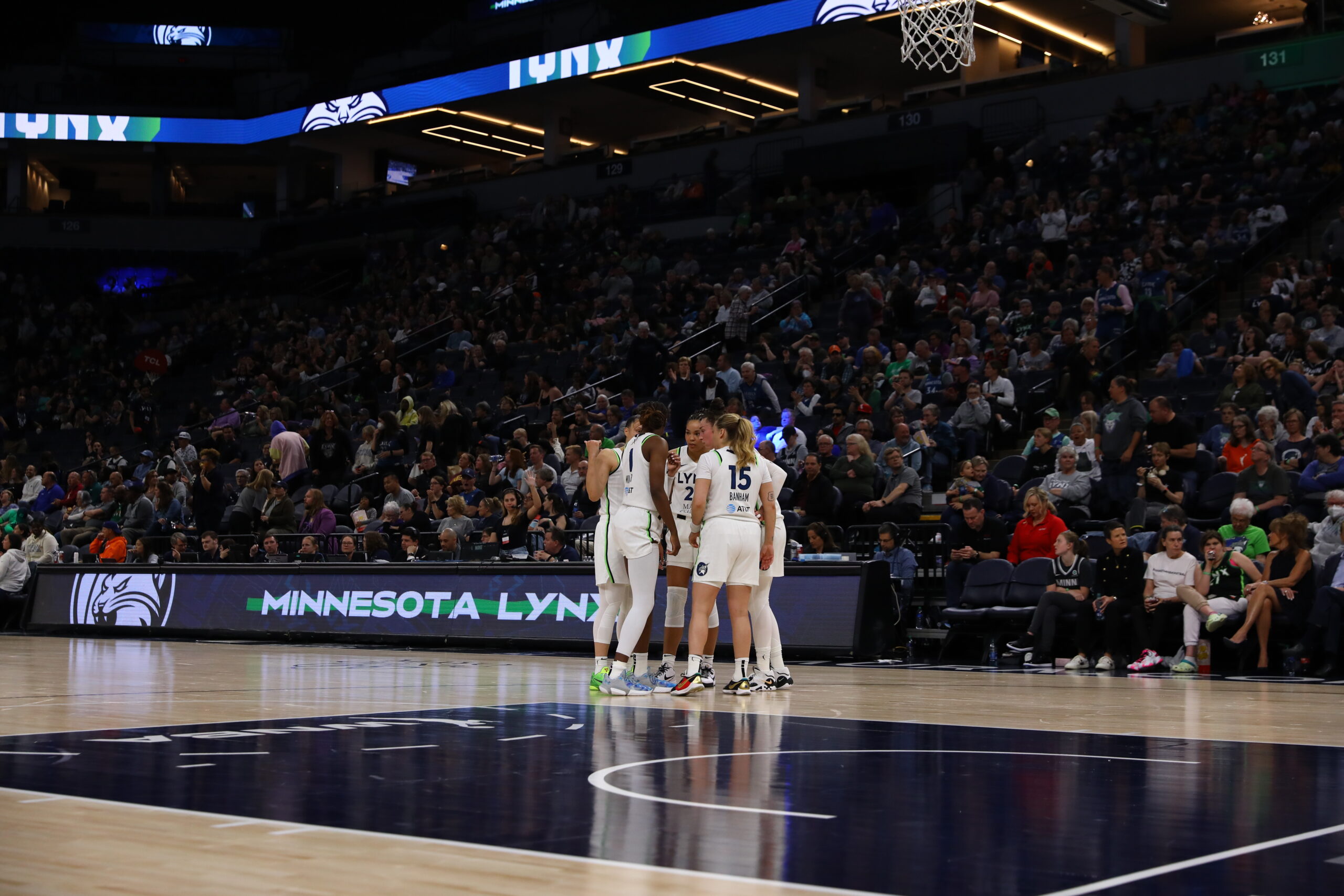 Five Minnesota Lynx players huddle near their bench.