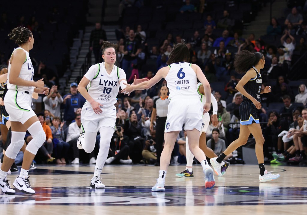 Minnesota Lynx forward Bridget Carleton reaches with her left hand to high-five center Jessica Shepard at mid-court as Shepard runs past her.