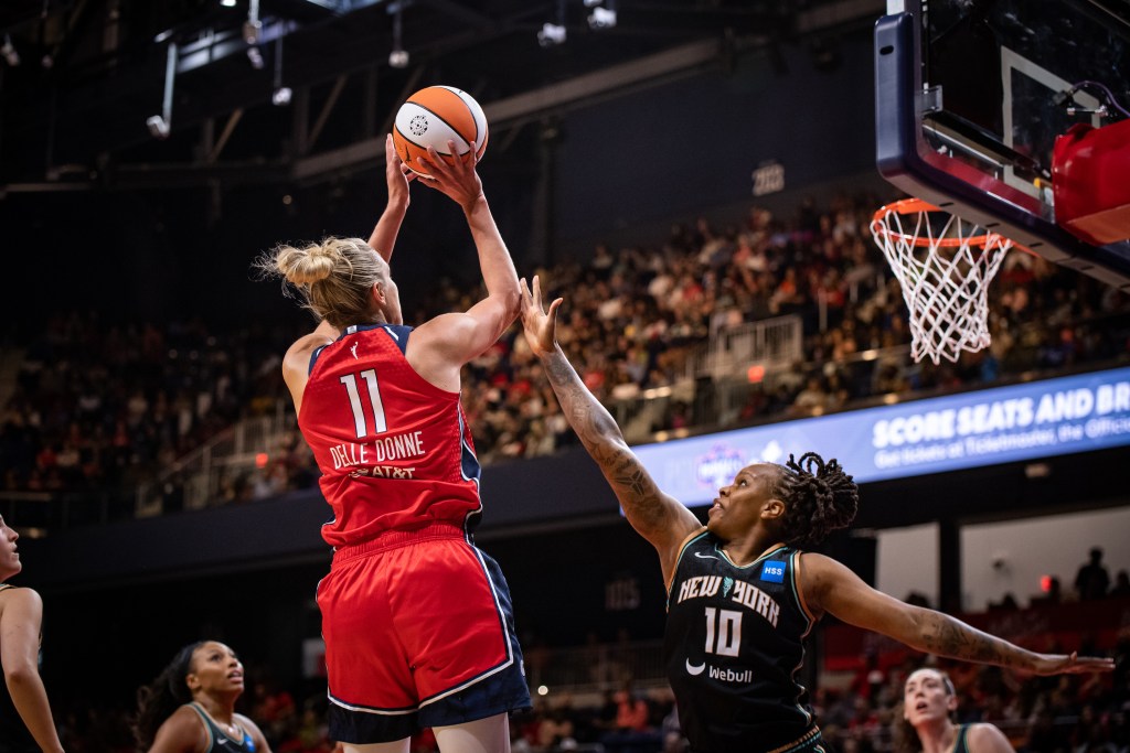 Washington Mystics forward/guard Elena Delle Donne shoots a short baseline jumper with her right hand. New York Liberty guard Epiphanny Prince contests the shot with her right hand and appears to make contact with Delle Donne's right elbow.