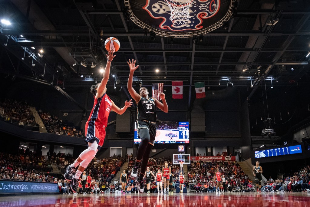 Washington Mystics guard Kristi Toliver shoots a layup in transition as New York Liberty center Jonquel Jones races back to try to contest it.