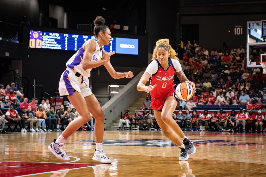Washington Mystics center/forward Shakira Austin dribbles with her left hand from near the top of the key, her eyes focused down at the lane ahead. A Los Angeles Sparks defender is at the elbow looking to cut off her drive.