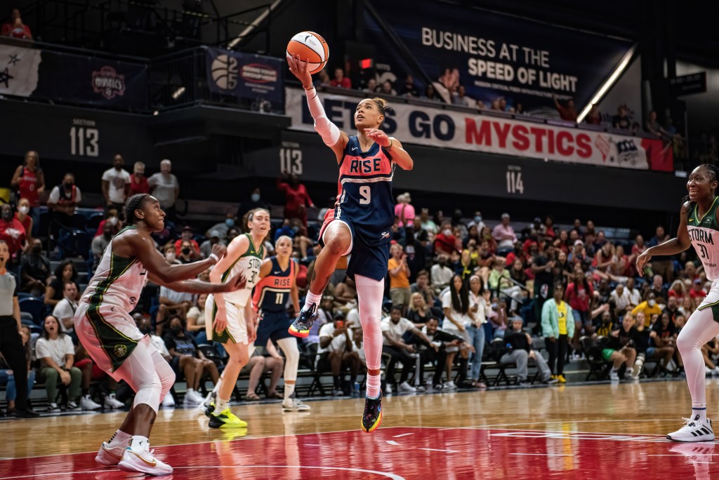 Washington Mystics guard Natasha Cloud attempts a right-handed layup in the middle of the lane. A Seattle Storm defender attempts to slide toward her but is too late.