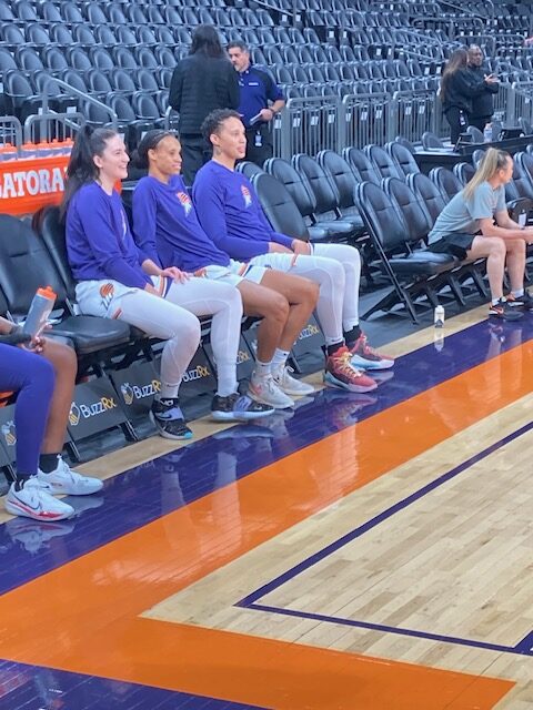 Brittney Griner sits with two of her teammates on the Phoenix Mercury bench.